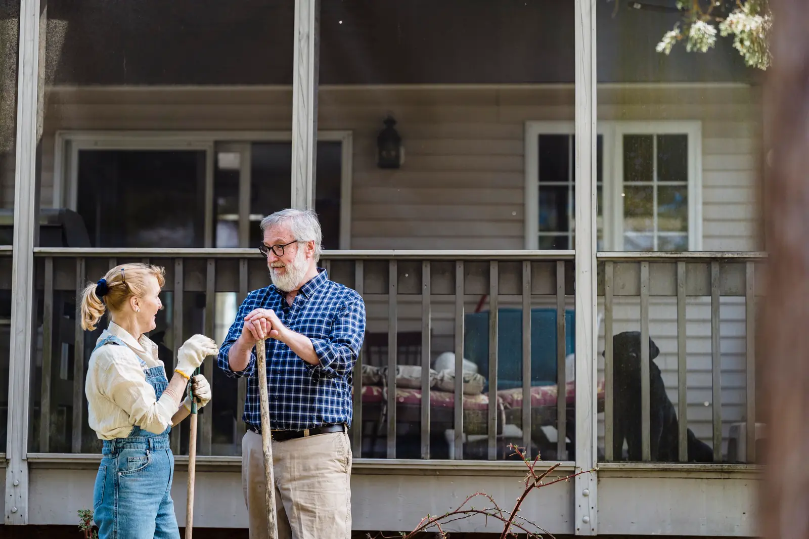 A Fernhollow gardener in overalls talking with a client on his back porch steps