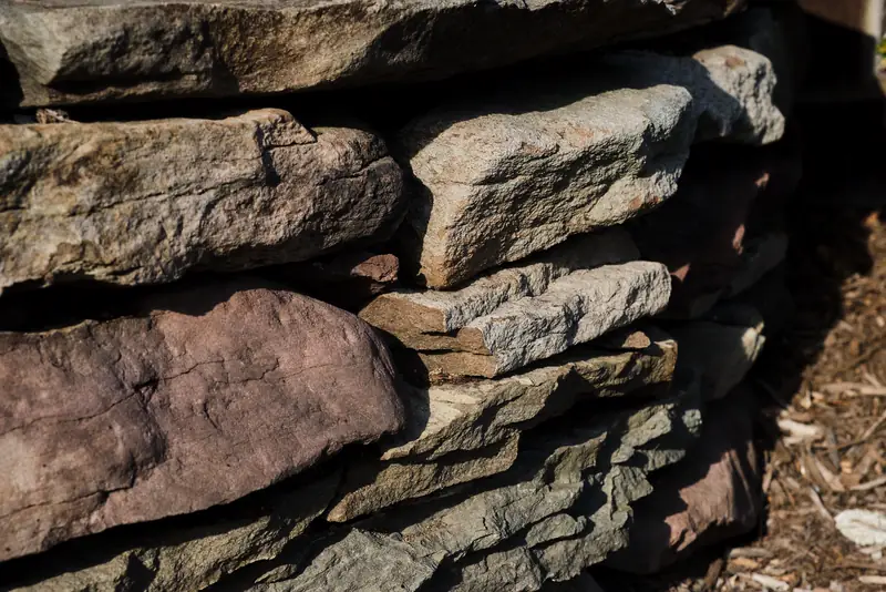 Close-up of flat fieldstones stacked dry, layer on layer, without mortar